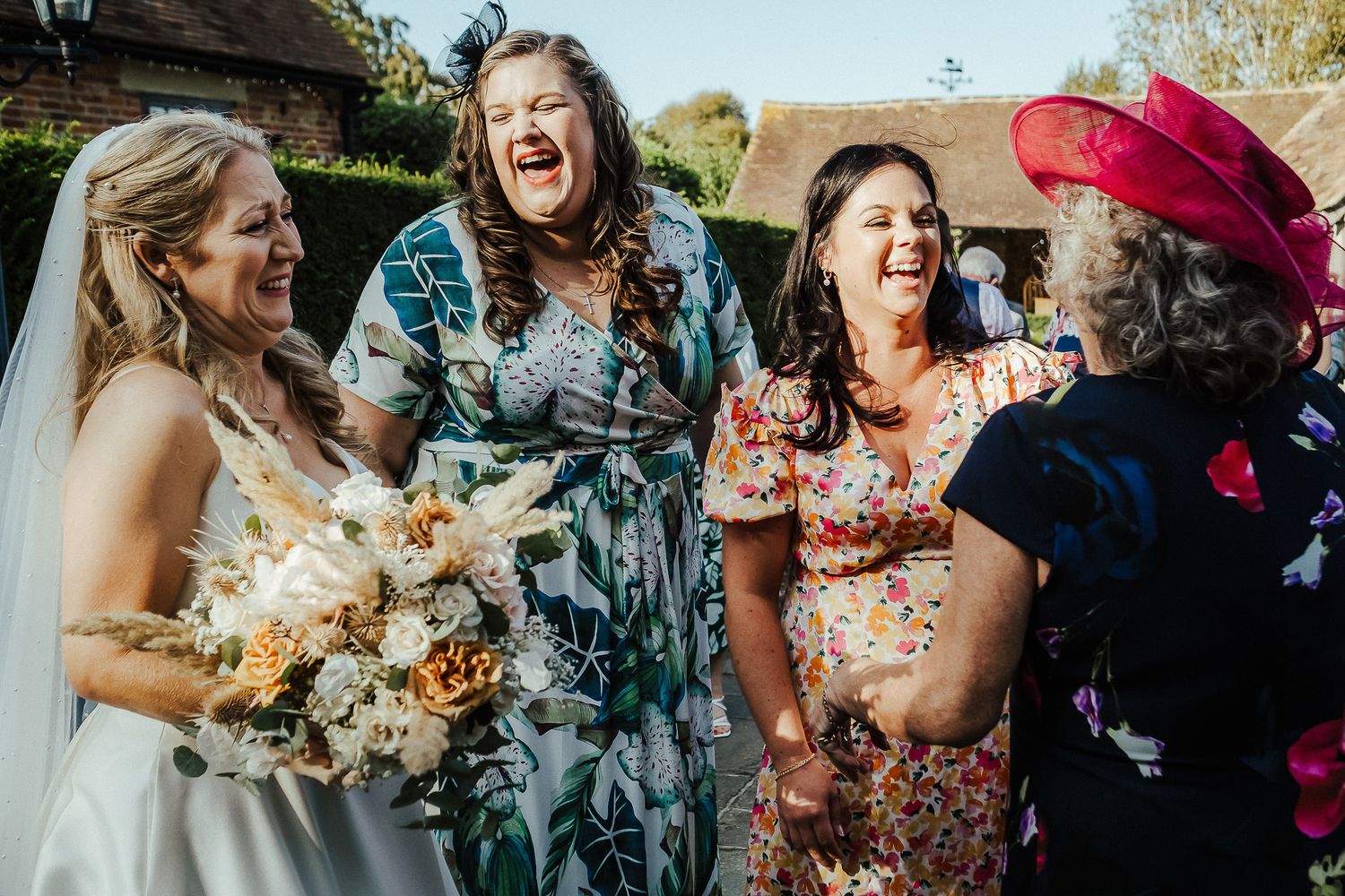 A joyous candid moment of laughter captured during a wedding celebration outdoors.