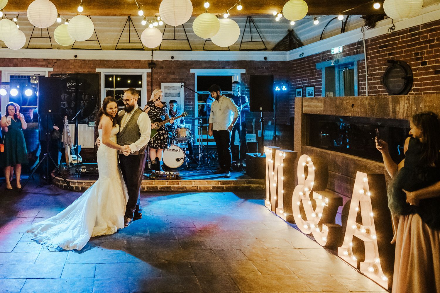 A wedding reception venue with illuminated letters and band setup on stage.