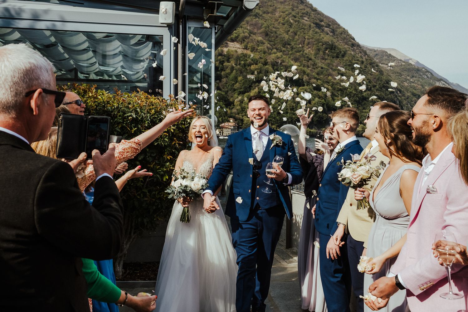 Wedding ceremony taking place outdoors with mountains and lake in the background.