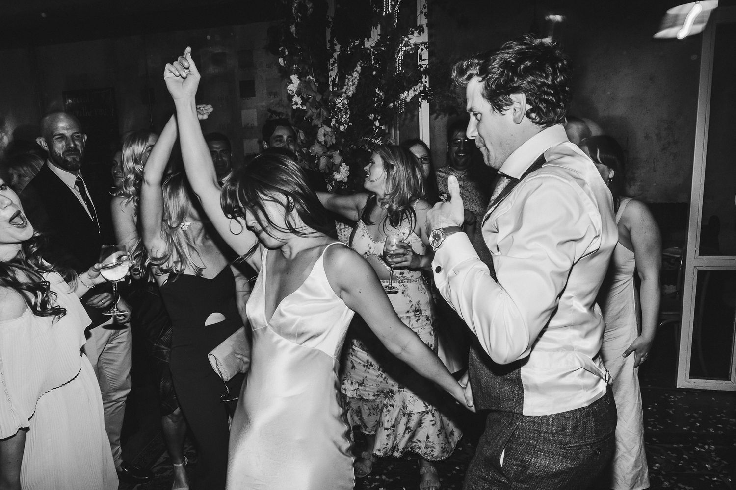 Black and white photo of energetic wedding reception dancing with guests on the dance floor.