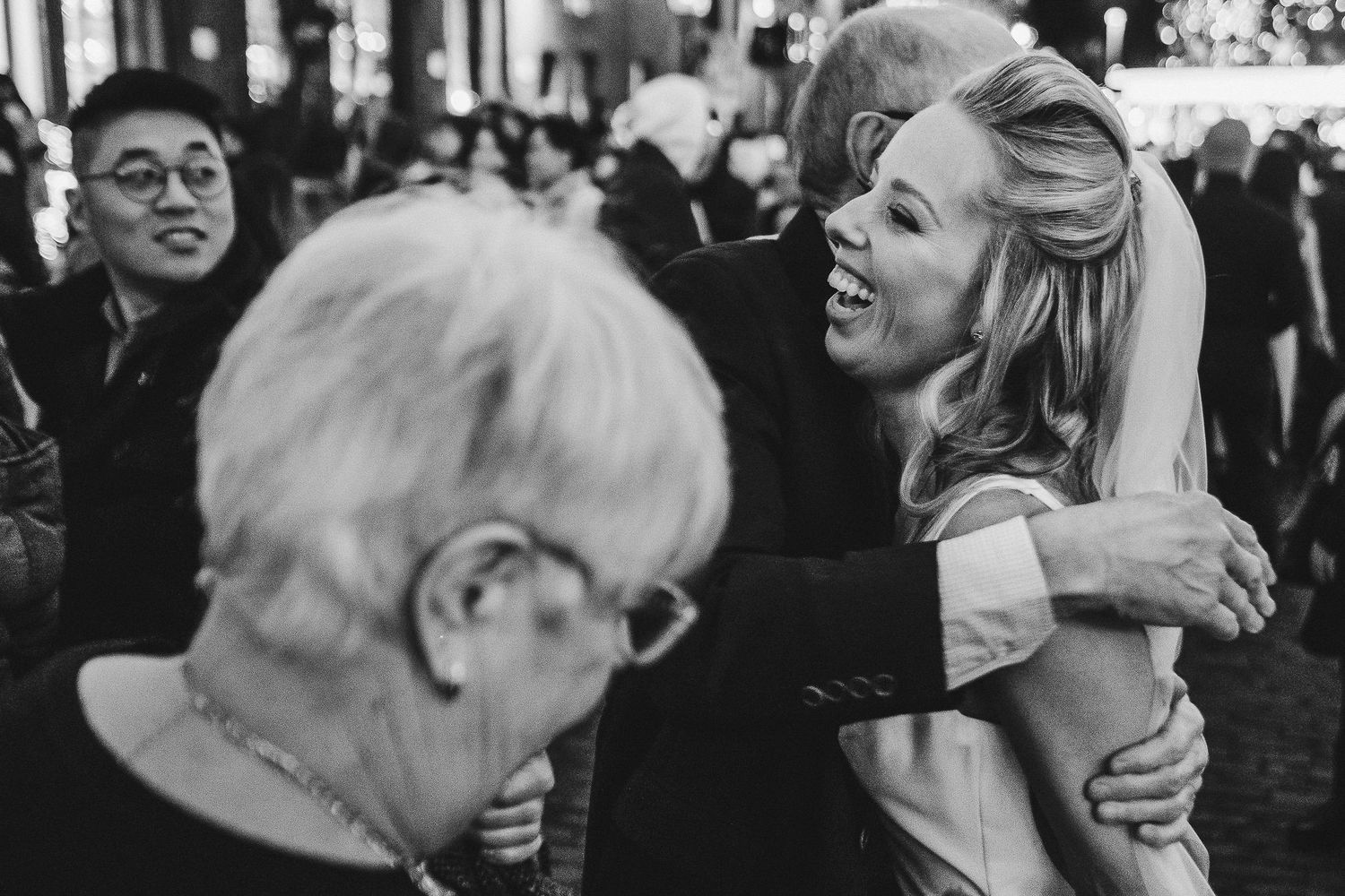 Black and white candid moment captured during wedding celebration in urban setting.