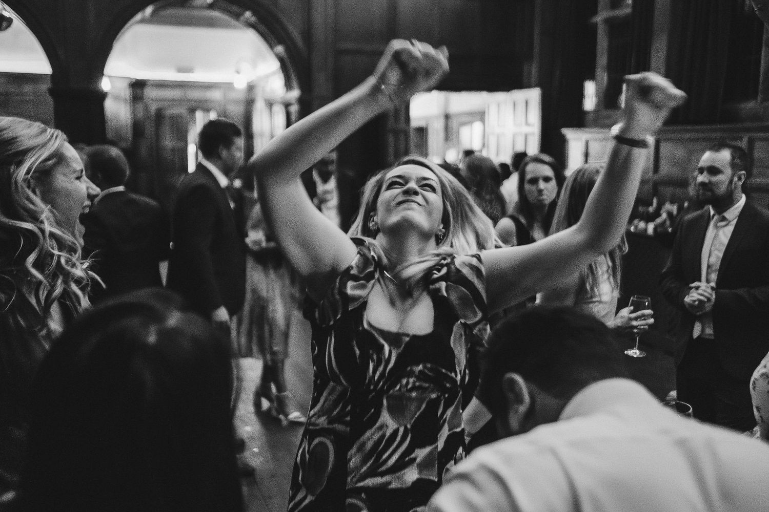 Black and white photo of guests celebrating joyfully on a dance floor.