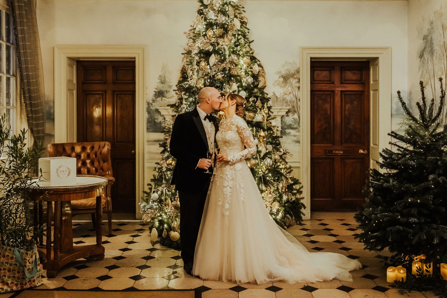 Elegant white floral arch adorns hallway entrance for winter wedding ceremony.