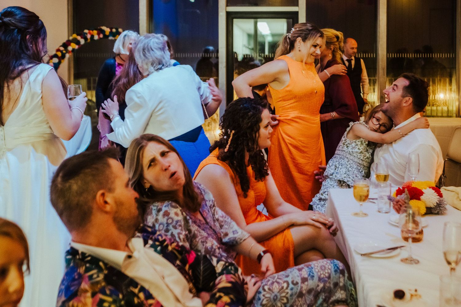 Wedding reception guests enjoying an animated conversation at decorated tables.