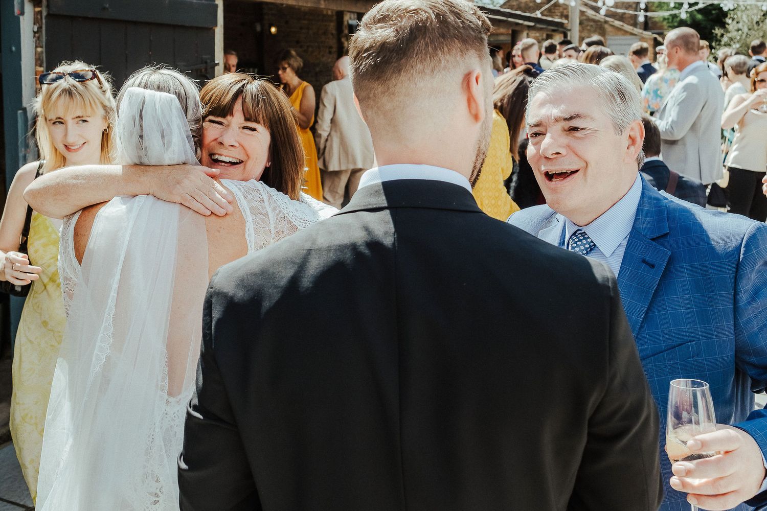Wedding guests laughing and celebrating at an outdoor reception.