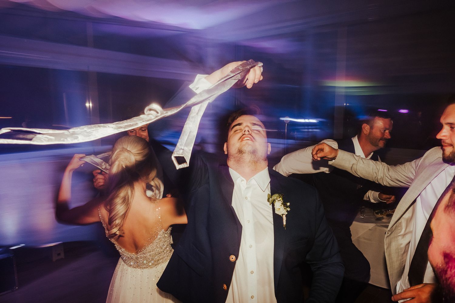 Wedding guests dancing enthusiastically with arms raised on a lively dance floor.