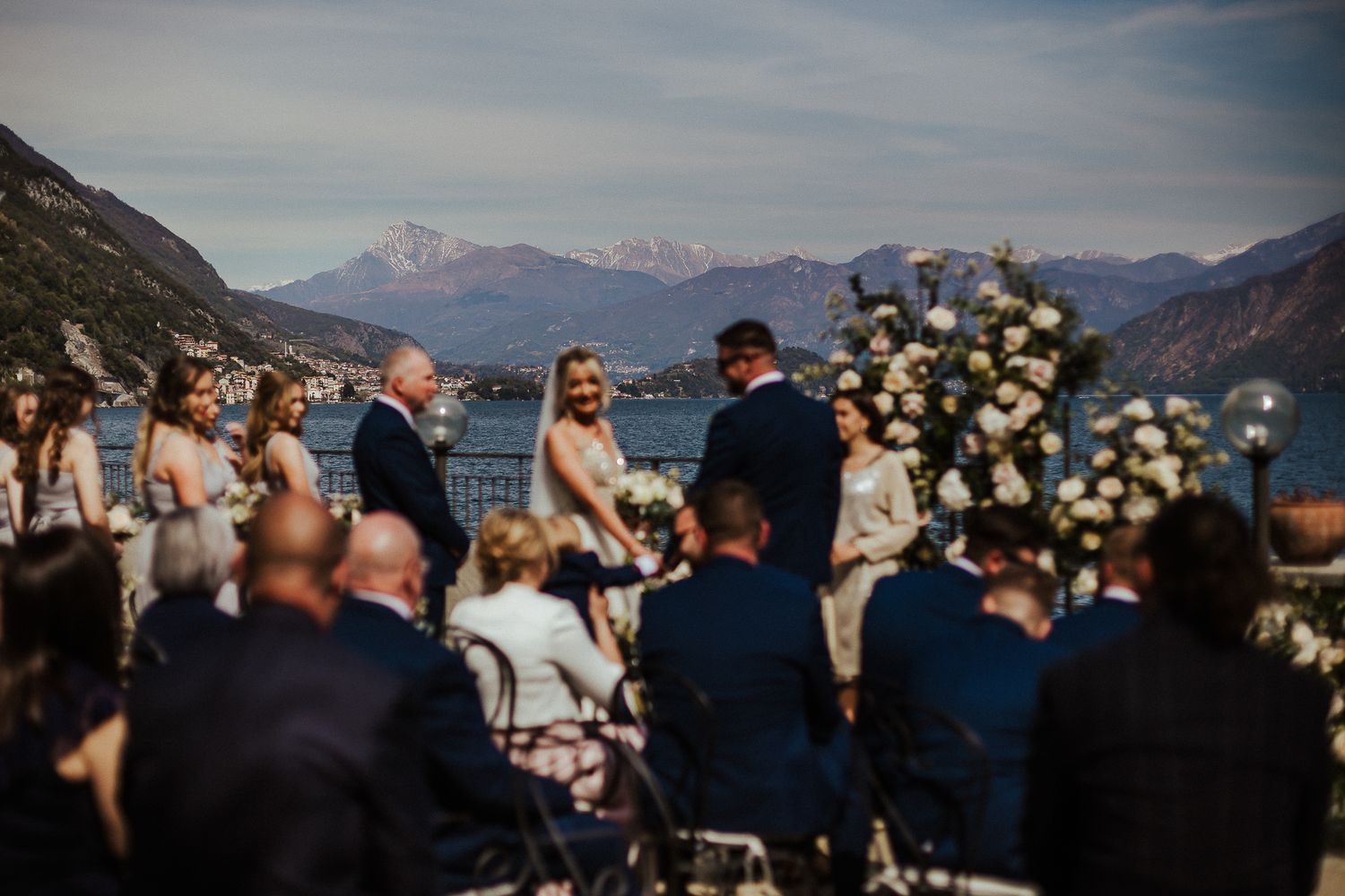 Wedding ceremony overlooking mountain lake with floral arch and seated guests.