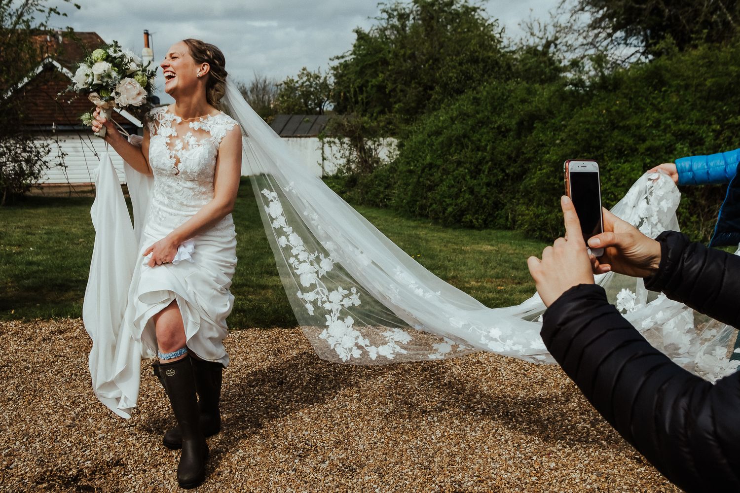 Wedding party posing playfully outdoors with flowing veil.
