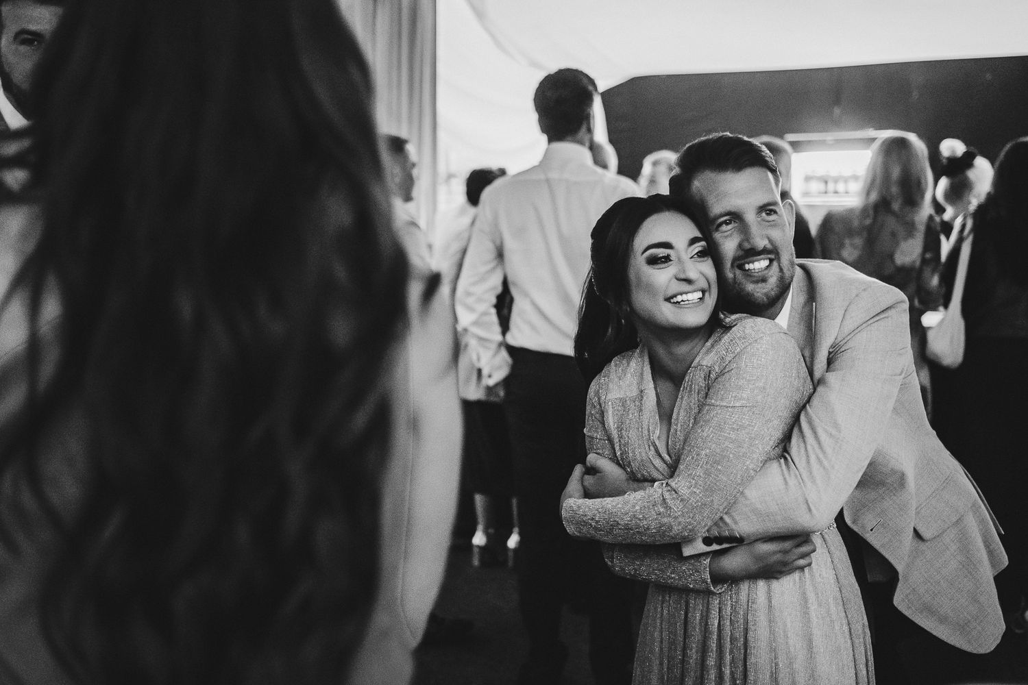 A couple embraces warmly while dancing at an indoor celebration event.