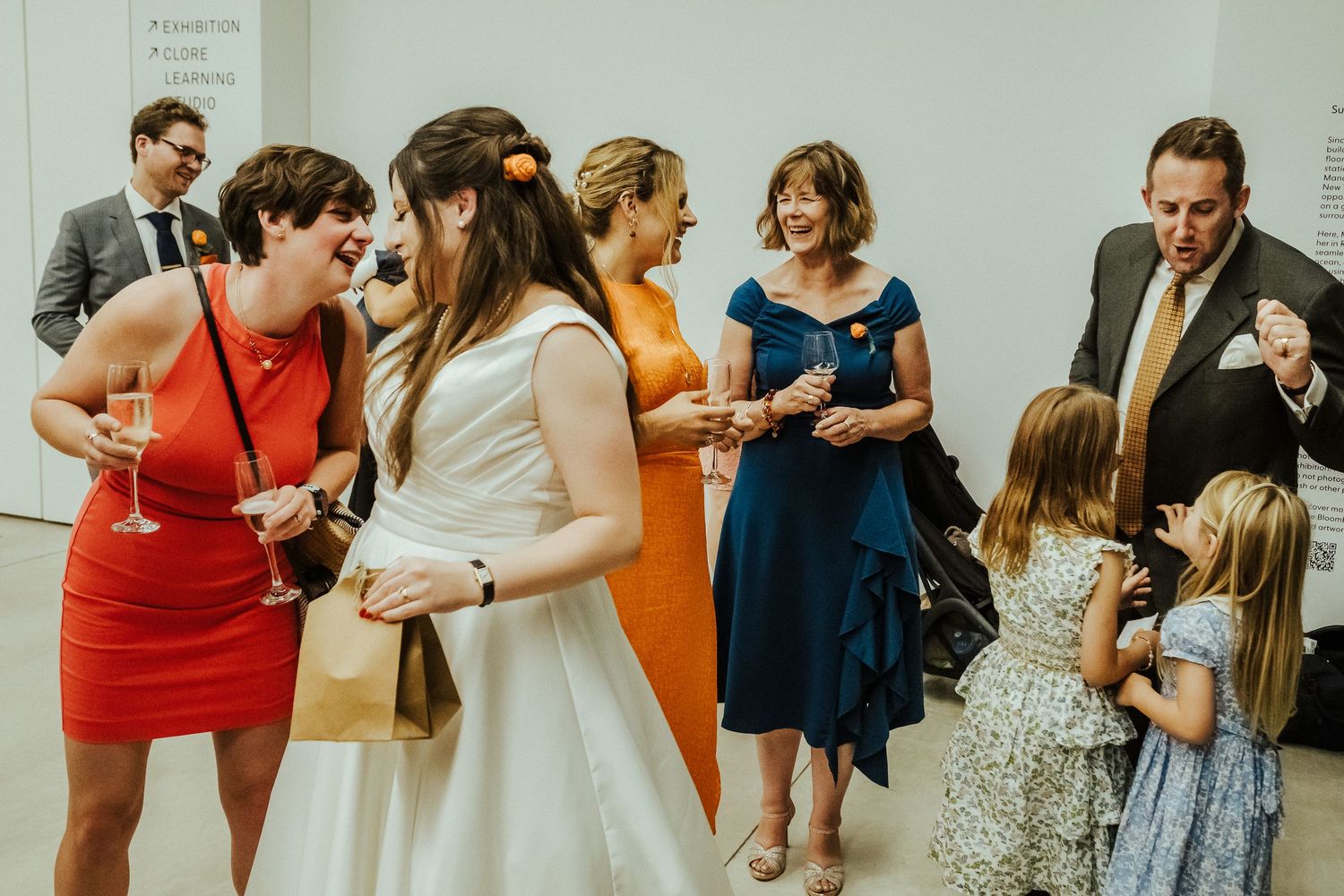 Wedding guests in colorful dresses socialize during a reception gathering.