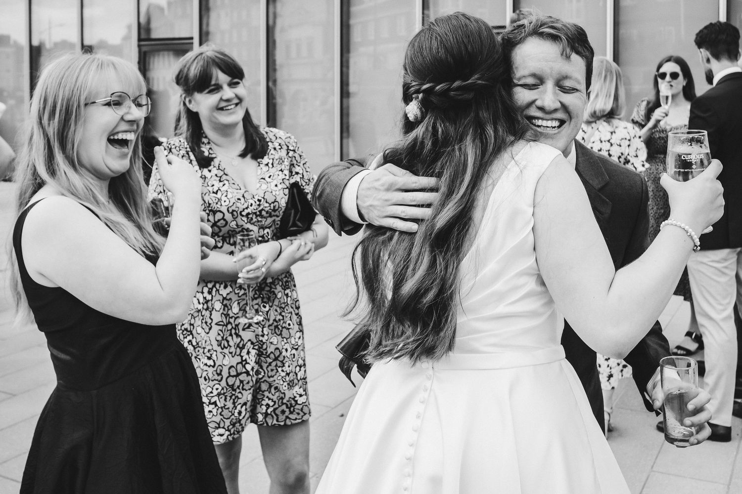 Black and white photo of joyful guests celebrating with the bride at a wedding.