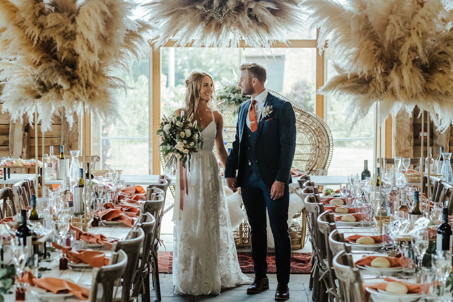 An elegantly decorated wedding reception venue with pampas grass decor and vintage table settings.