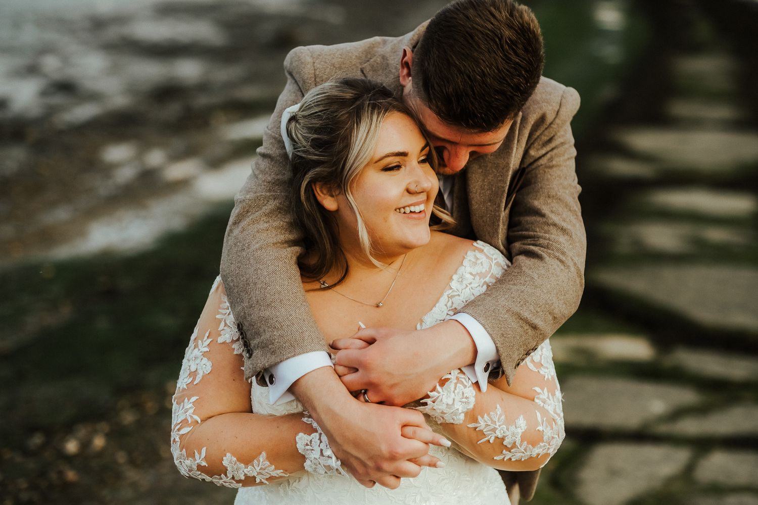 A joyful embrace captured in warm sunlight during an outdoor wedding celebration.