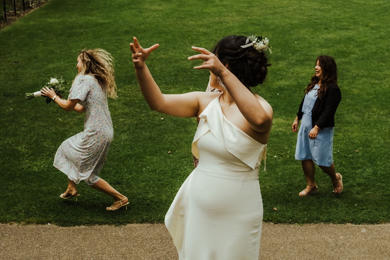 Group of wedding guests throwing white confetti on a grassy lawn.