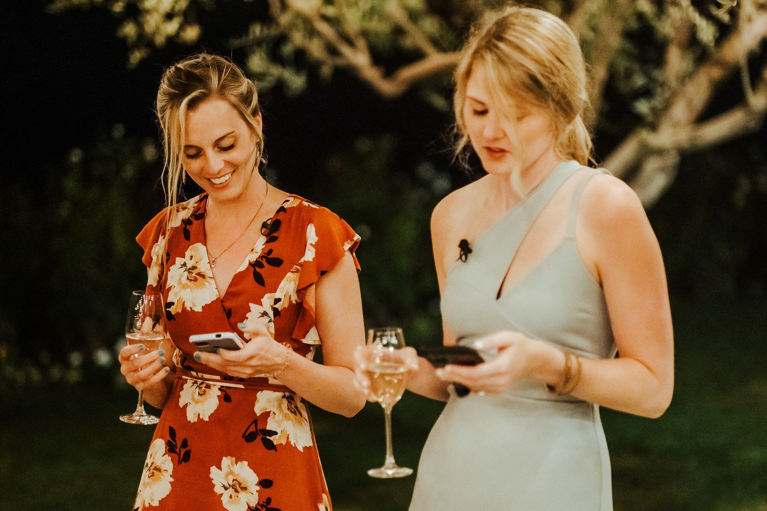 Guests in floral and pastel dresses enjoy drinks at an outdoor celebration.