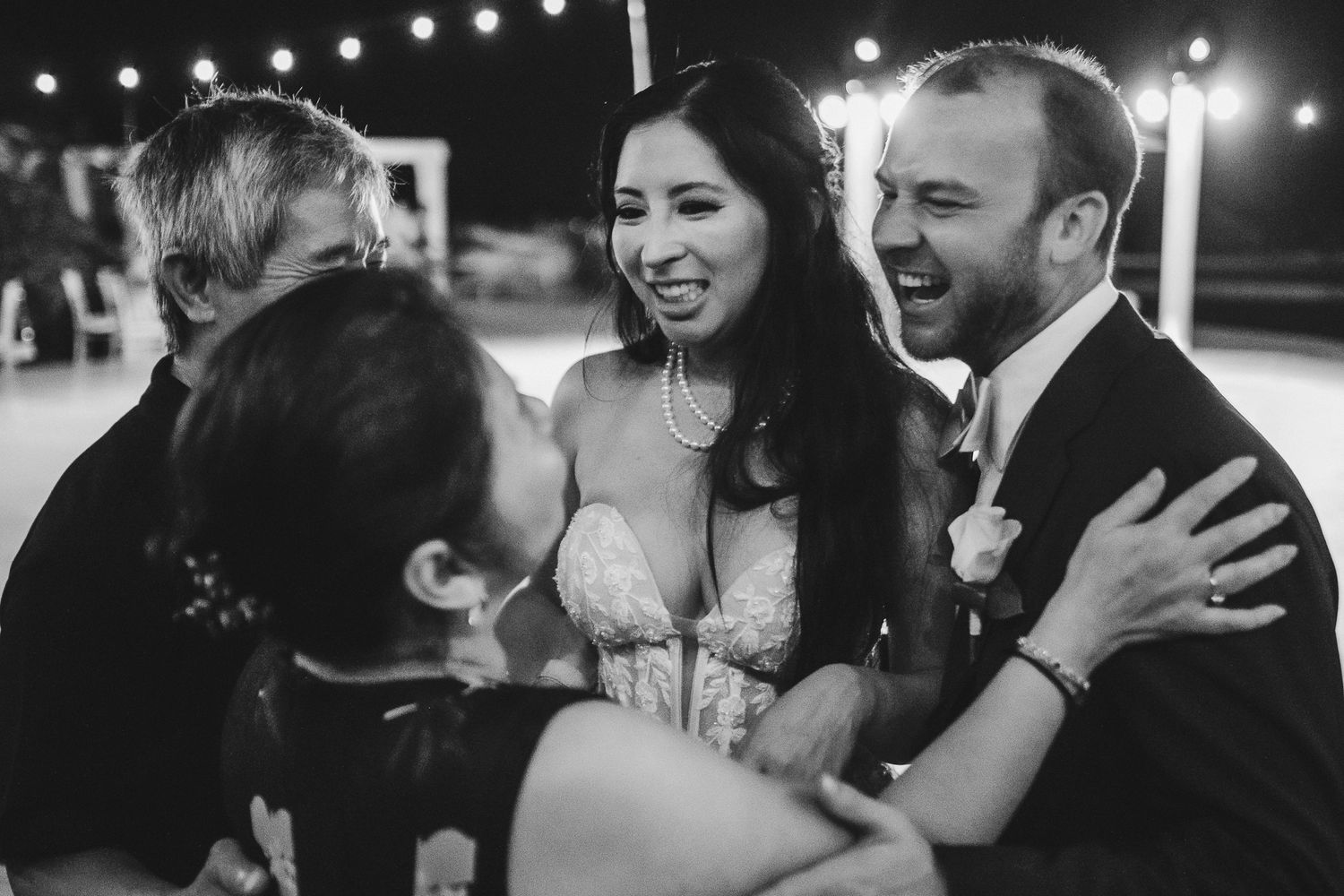 Black and white candid photo of joyful laughter at nighttime wedding celebration.