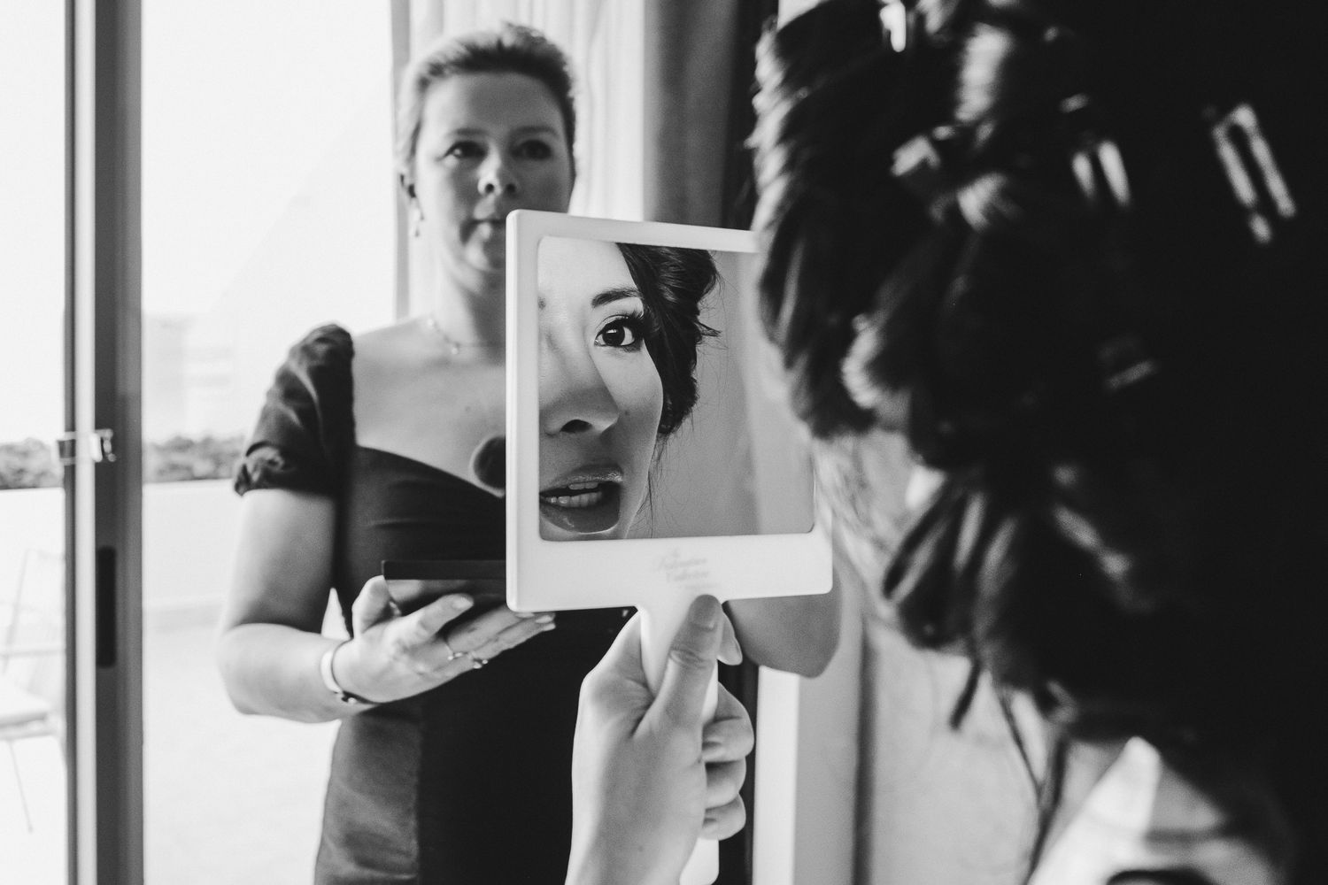 Black and white behind the scenes photo showing a Polaroid photo being held up during wedding preparations.