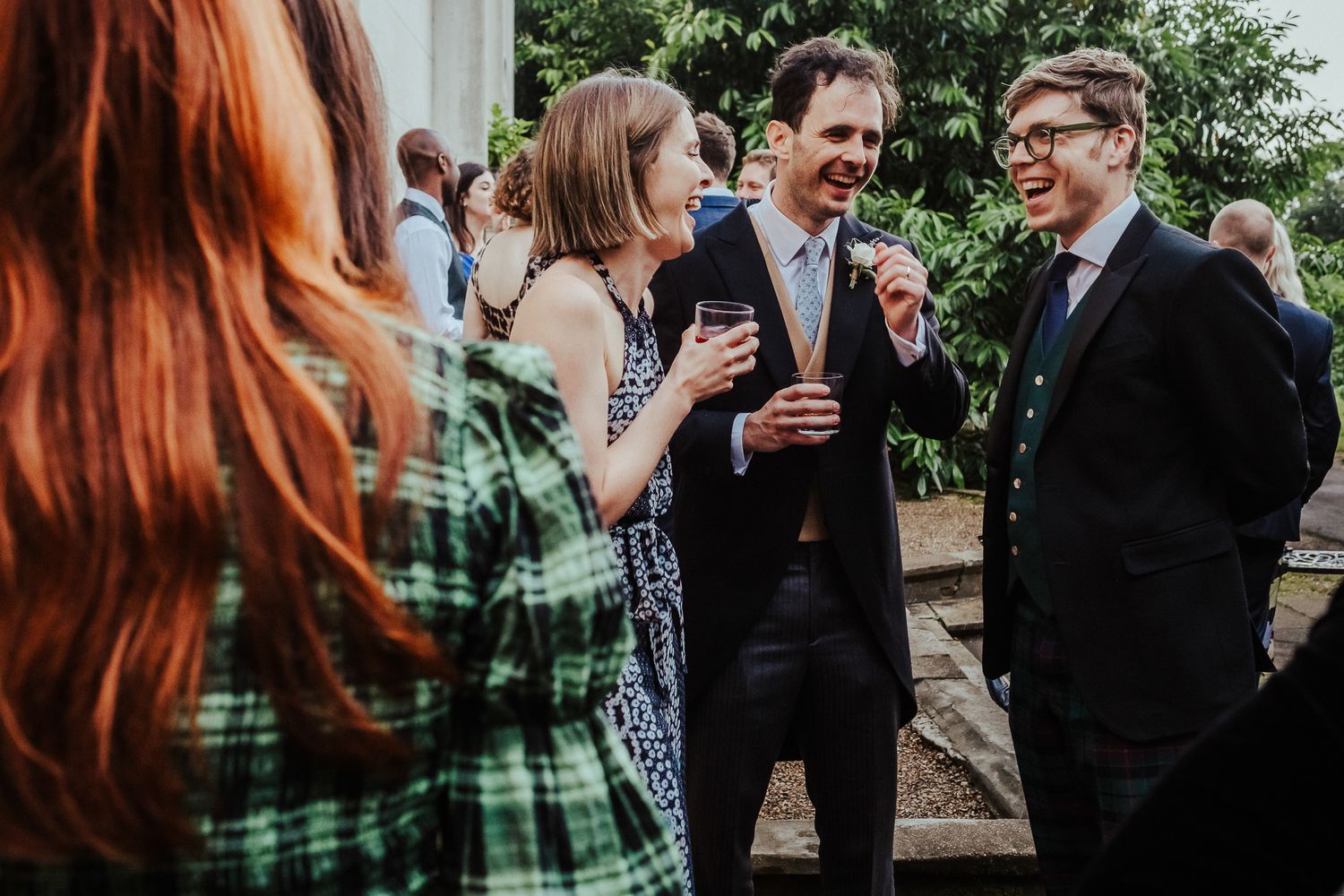 Guests chatting and laughing at an outdoor wedding reception.