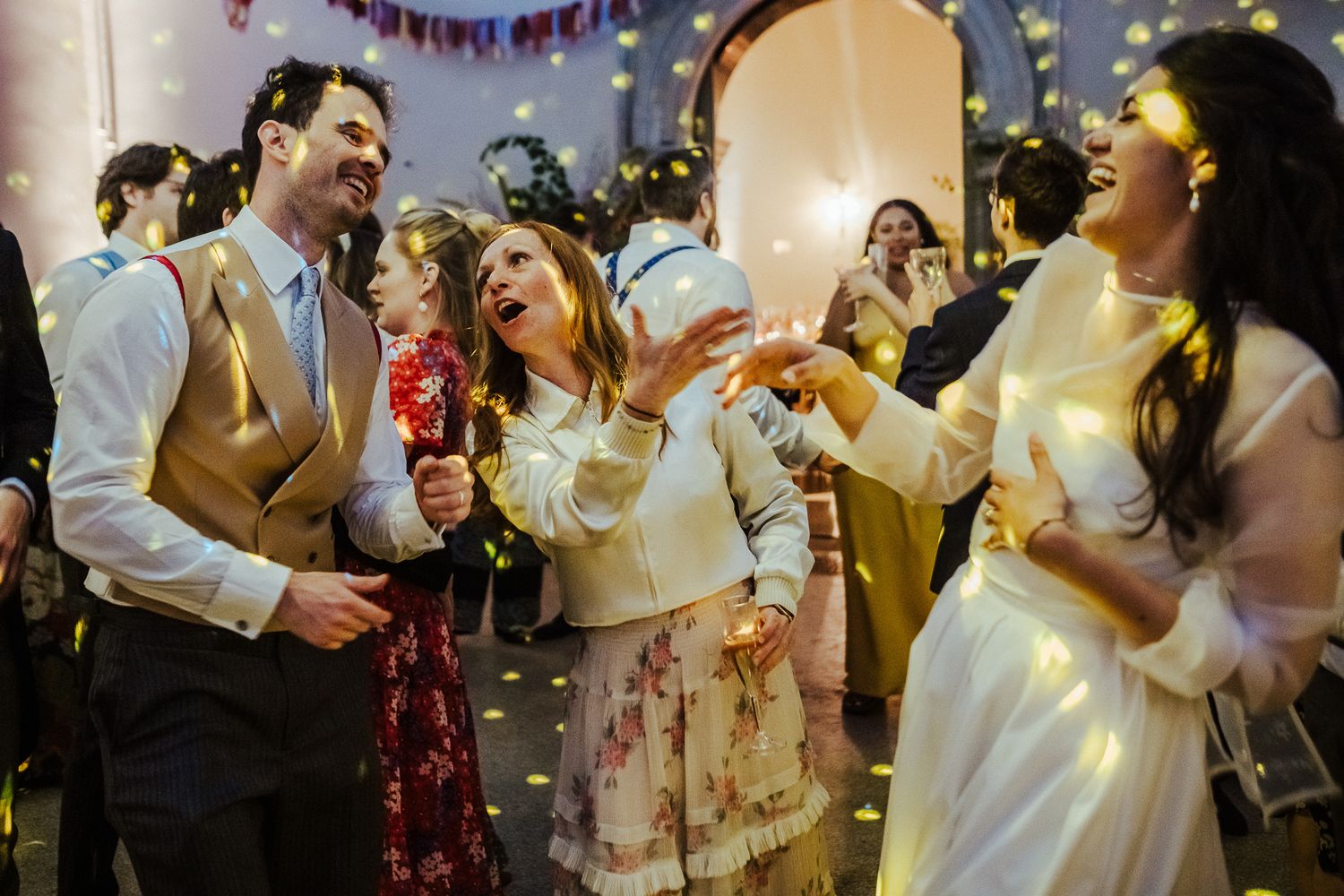 Guests enjoying themselves at a festive indoor celebration with confetti and string lights.