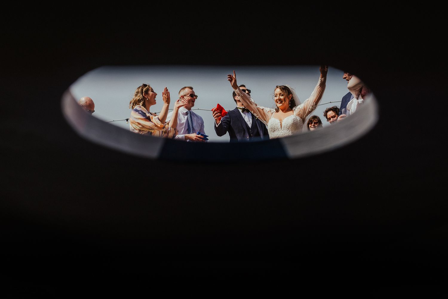Artistic framed shot of wedding guests celebrating through a narrow viewing angle.