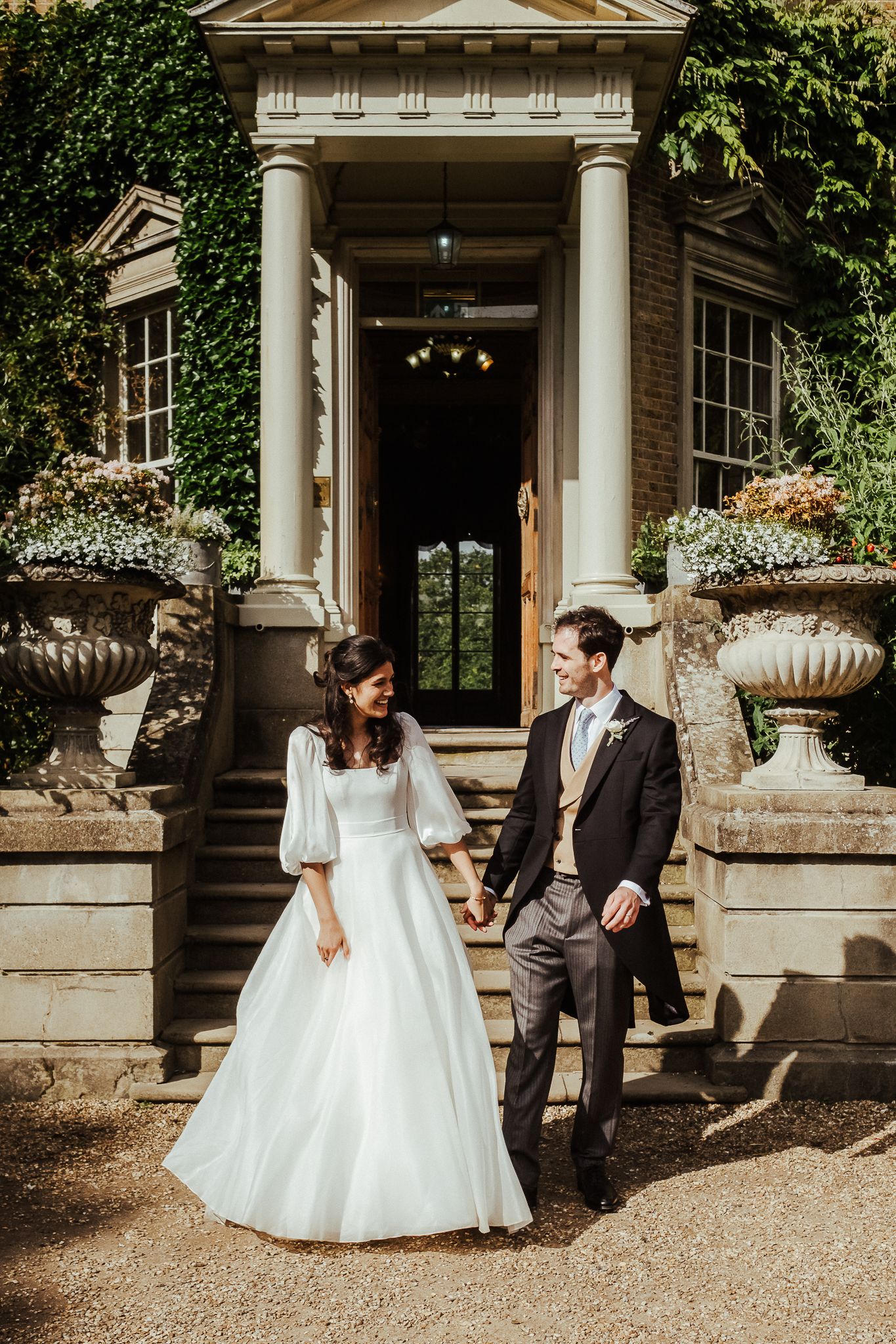 Elegant wedding portraits taken outside a historic mansion with classical columns.