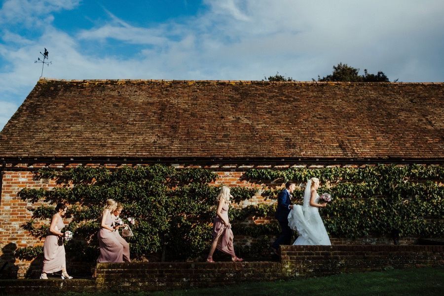 Panoramic view of a rustic barn venue with guests celebrating under blue sky.