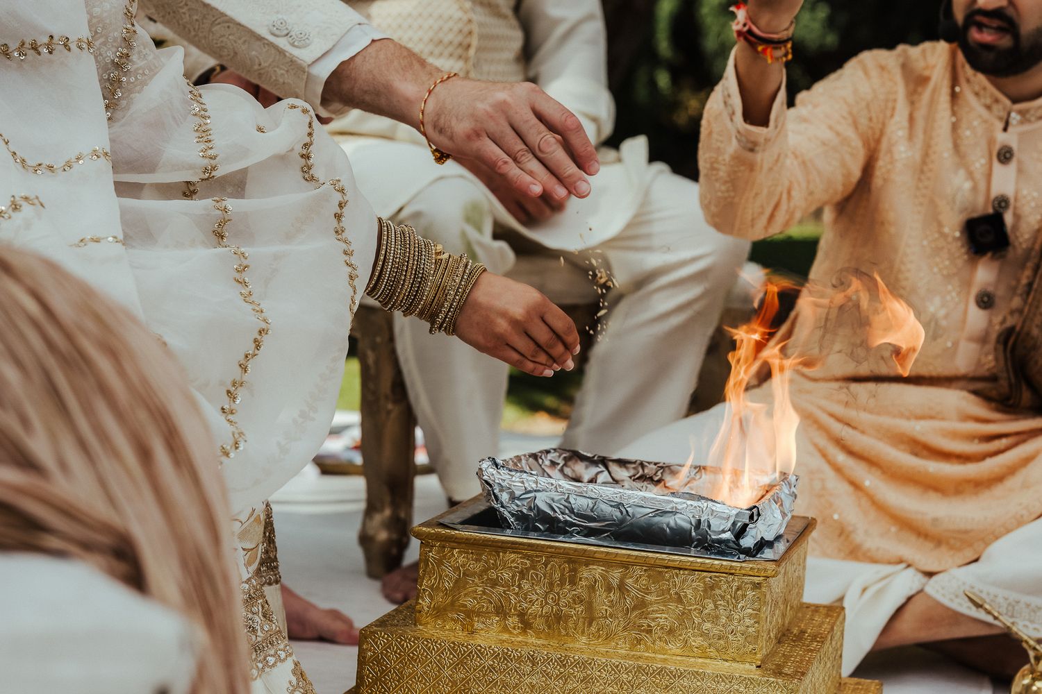 Traditional Middle Eastern gathering with people seated around and sharing food from a golden tray near a campfire.