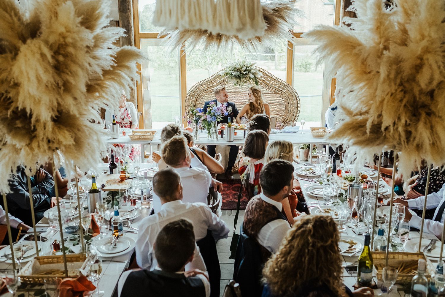 A wedding reception celebration with pampas grass decor and festive table settings.