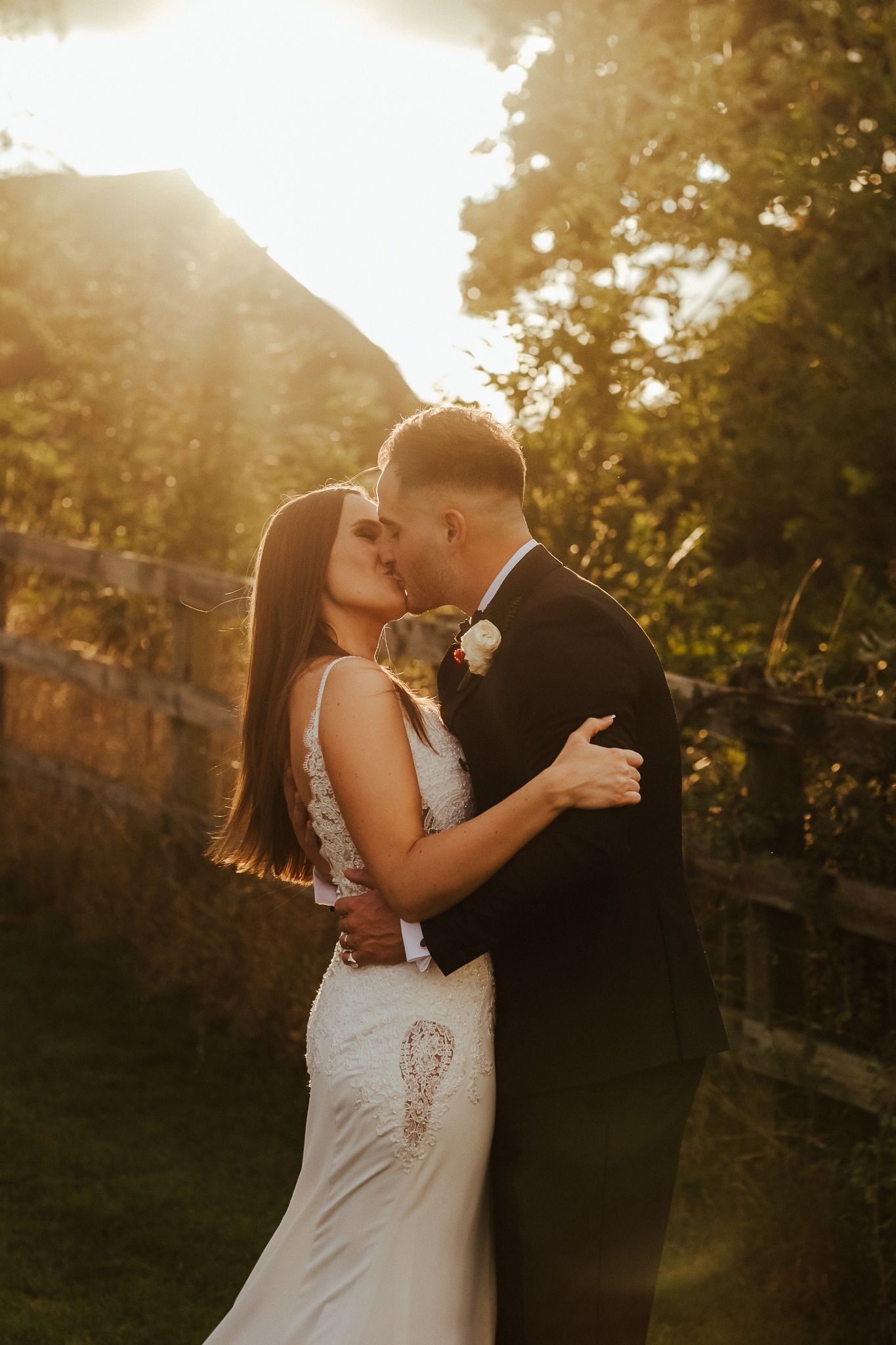 Romantic sunset portrait of newlyweds embracing in golden hour light.