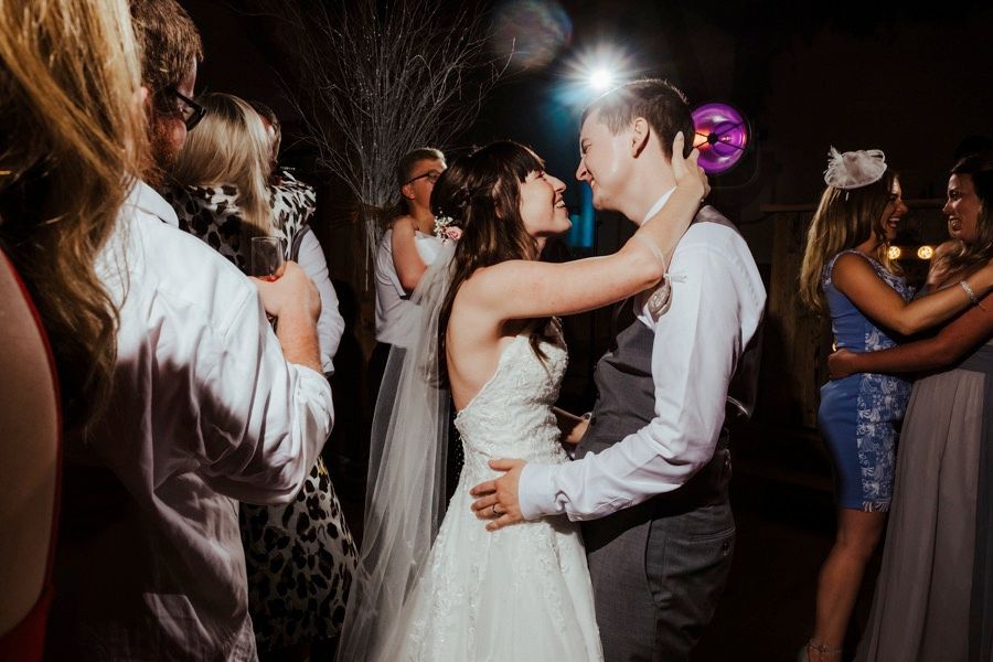 A couple shares their first dance at a wedding reception while guests watch and celebrate.