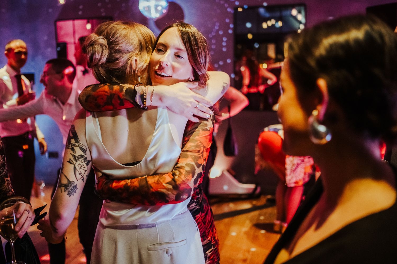 Dance floor filled with celebration under dramatic purple and red lighting.