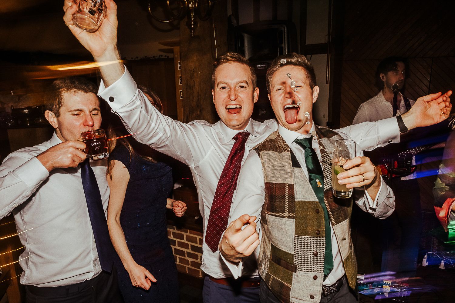 Wedding reception party with energetic dancing and celebrations in dimly lit venue.