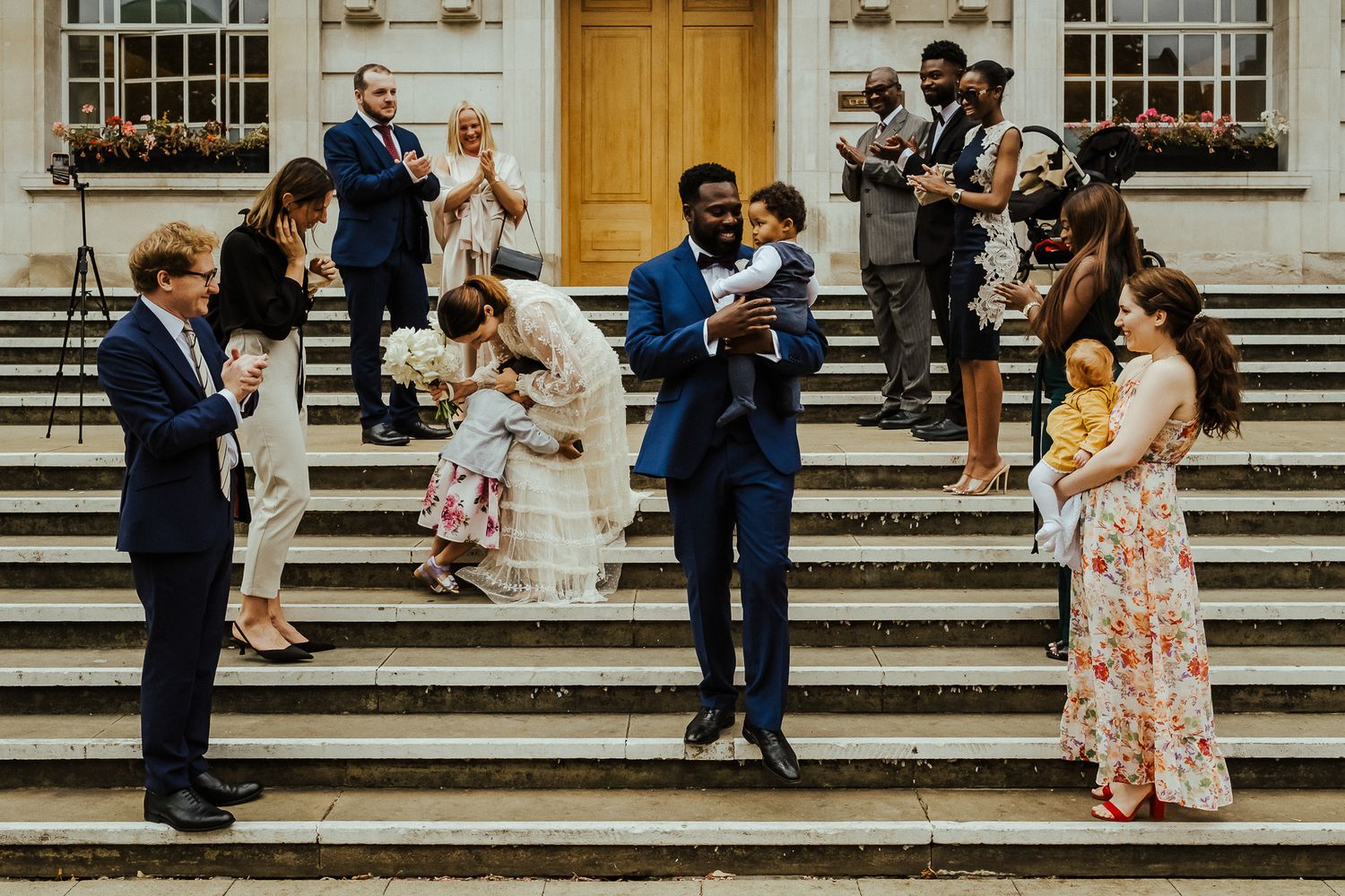 Wedding guests gathered on grand stone steps outside historic building.