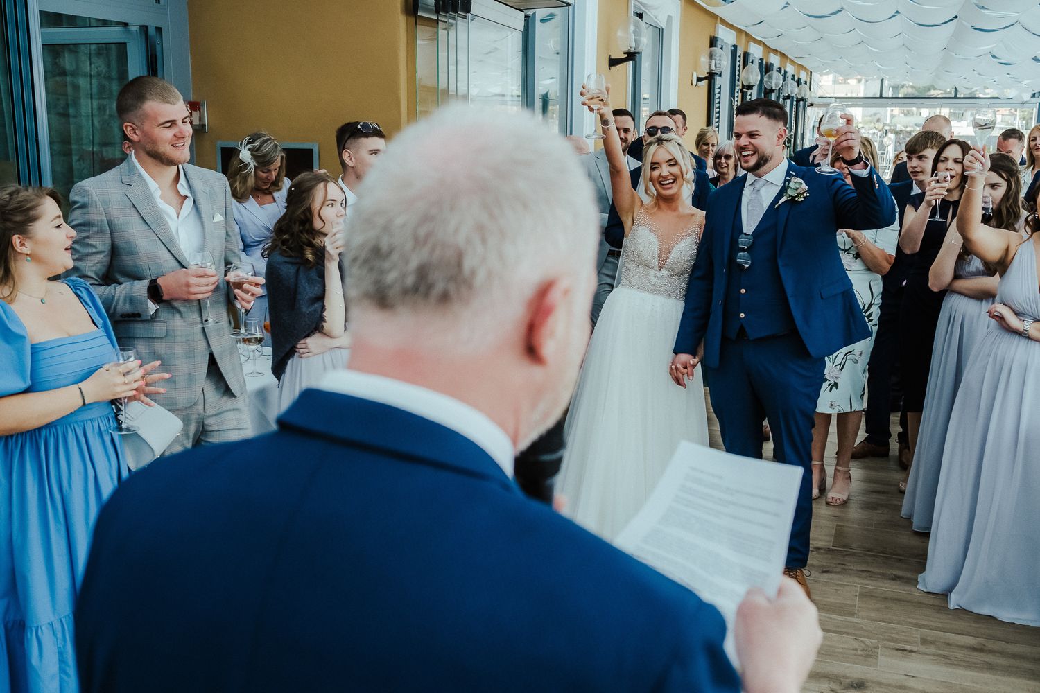 Wedding ceremony guests watch attentively during an indoor celebration.