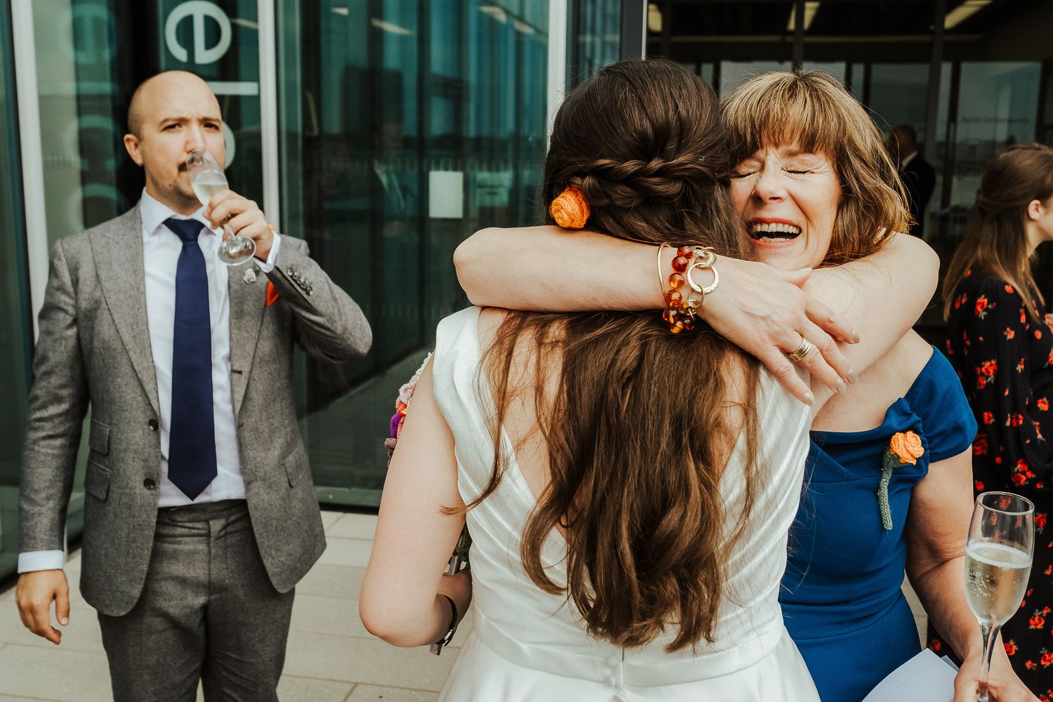 Joyful wedding celebration moments captured in front of a modern glass building.
