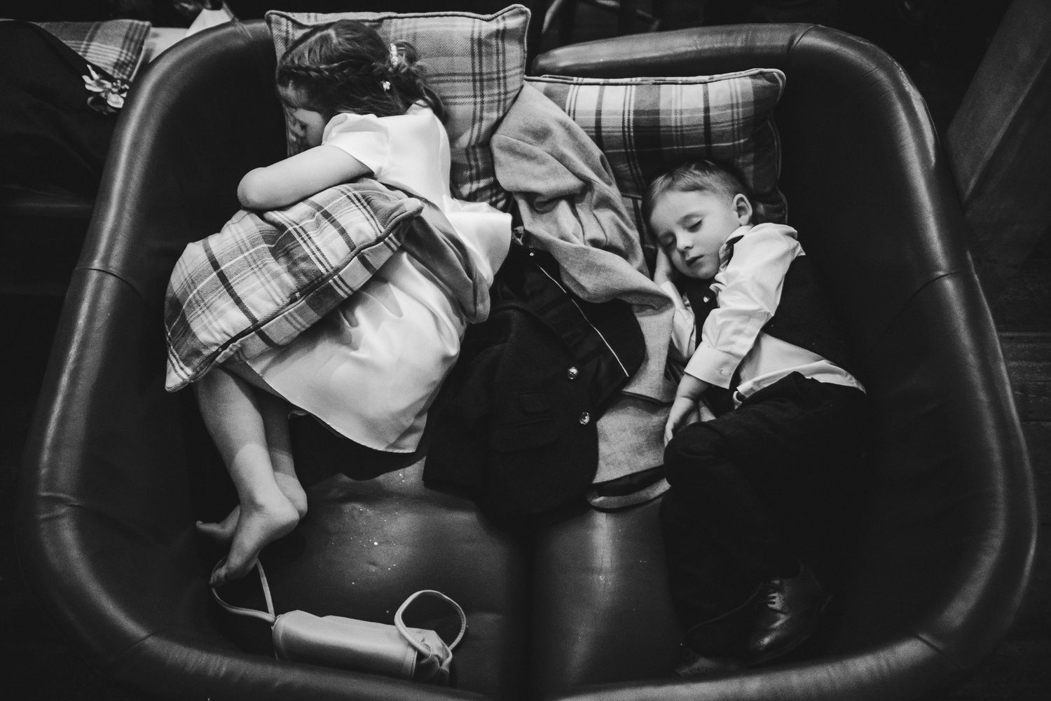 Black and white overhead view of children sleeping in plaid outfits.