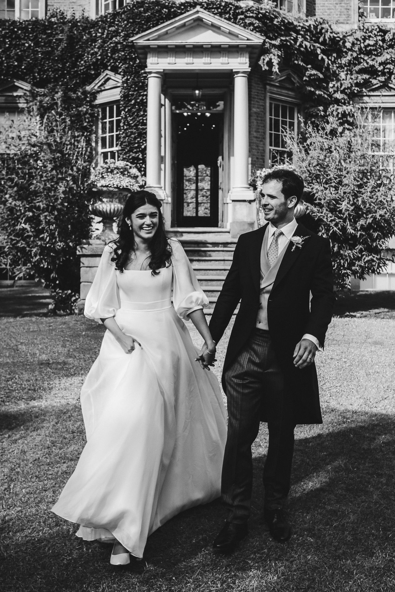 Black and white wedding portraits on the grounds of a stately mansion.