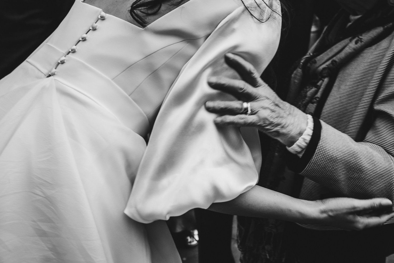 Close-up shot of hands and formal attire at an elegant wedding celebration.