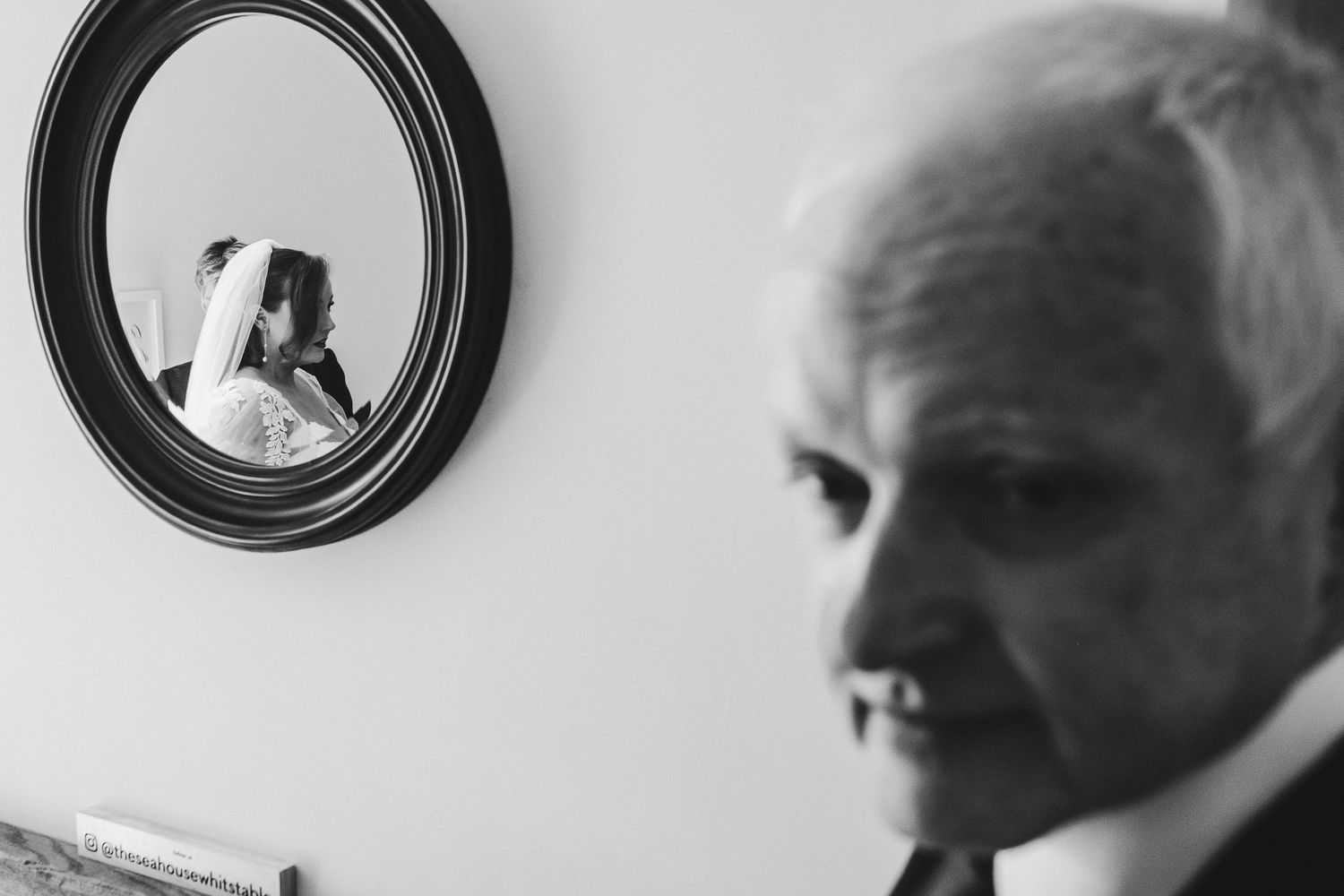 Artistic black and white photo showing a reflection in a round mirror on a white wall.