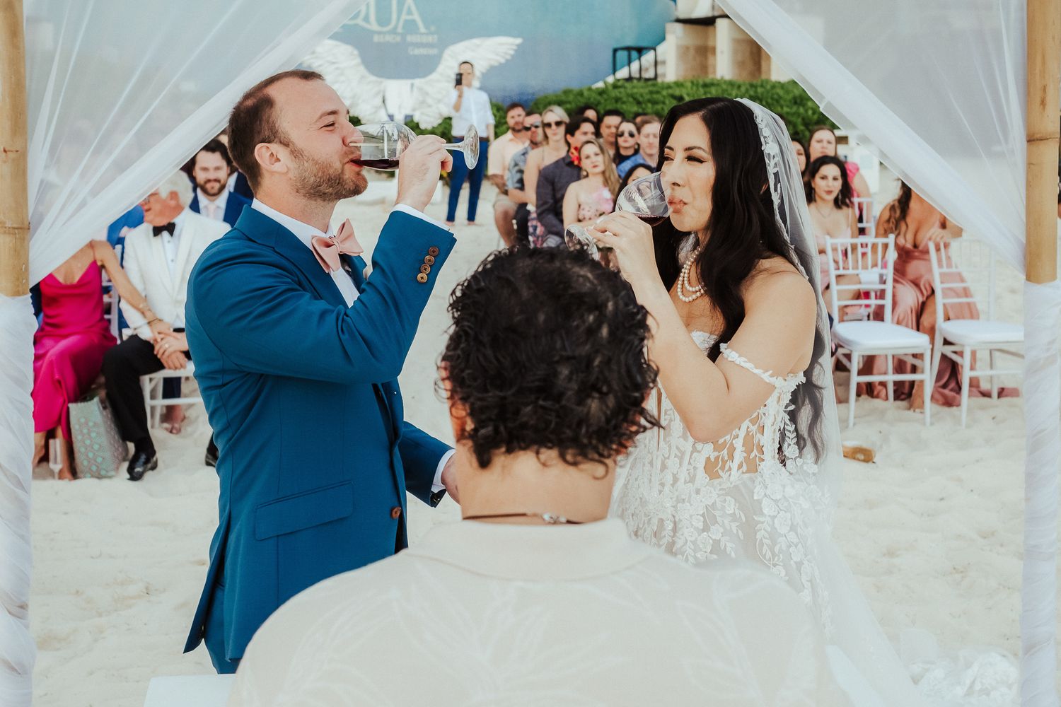 Wedding celebration under a white tent with guests enjoying a lively moment.