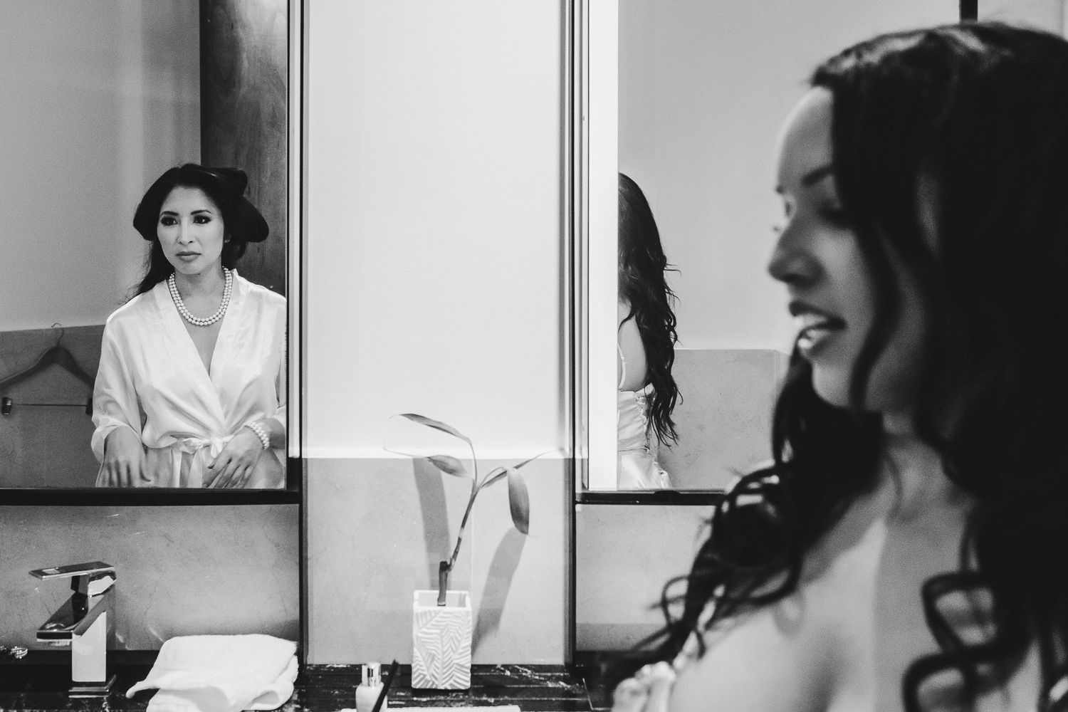Artistic black and white reflection shot of a bride looking in the mirror during wedding preparations.