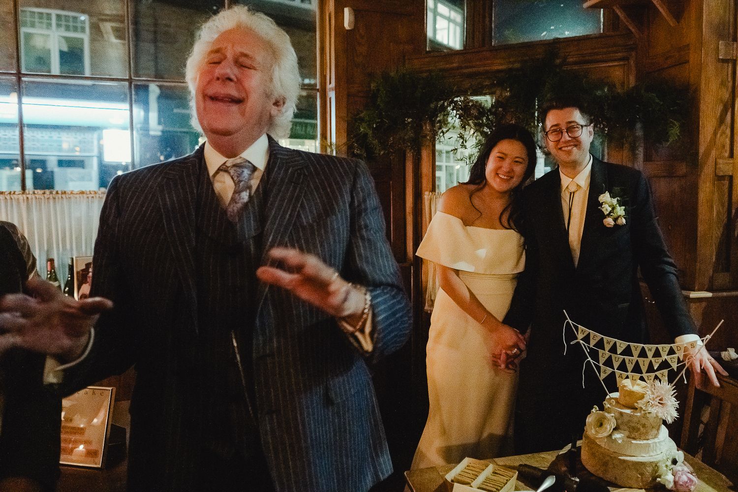 A wedding celebration montage showing guests mingling and toasting in a cozy rustic venue with wooden beams and warm lighting.