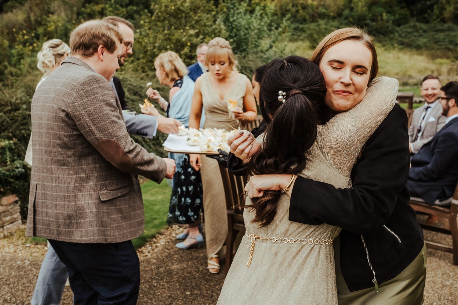 Wedding guests share slices of pie and desserts at an outdoor reception celebration on rustic wooden tables.