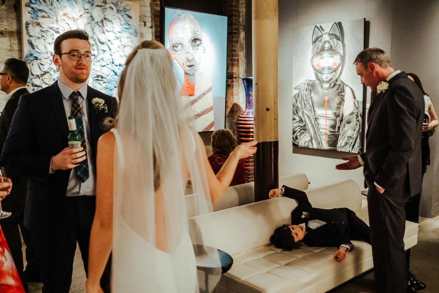 Wedding party exploring an art gallery venue with modern artwork on display.