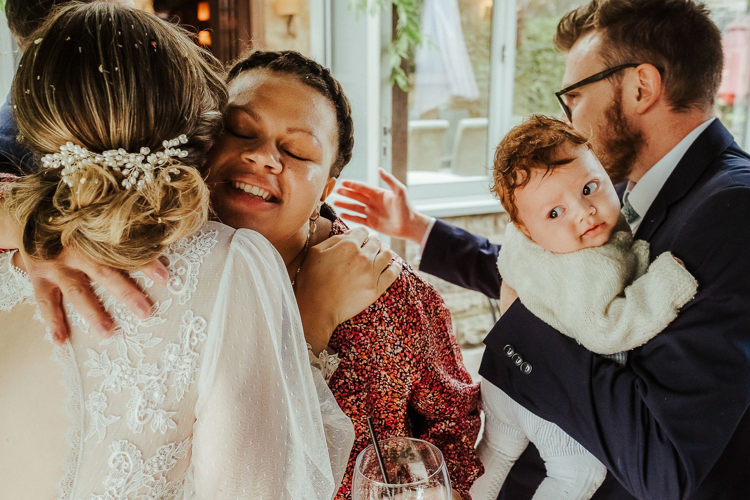 Joyful wedding celebration with baby and bridal party sharing emotional moments together.
