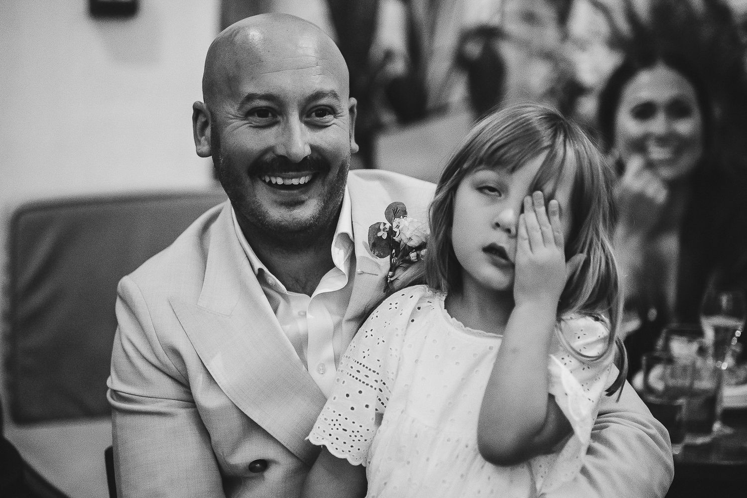 A candid black and white moment shows a playful interaction at a wedding reception.