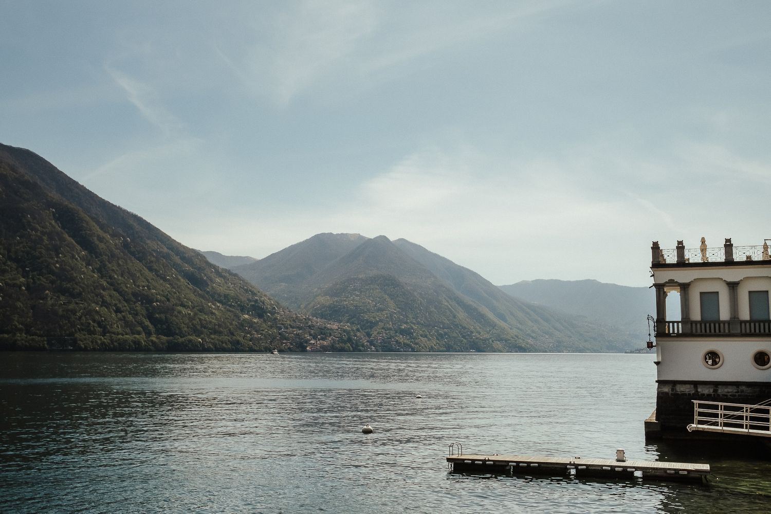 Scenic mountain lake landscape with a dock and traditional architecture.