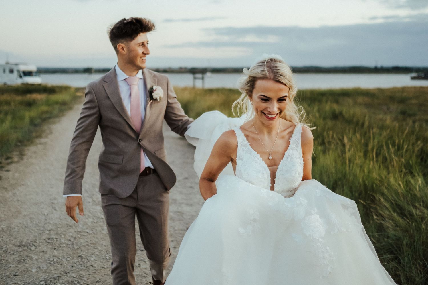 A couple walks along a coastal path during their wedding photo session.