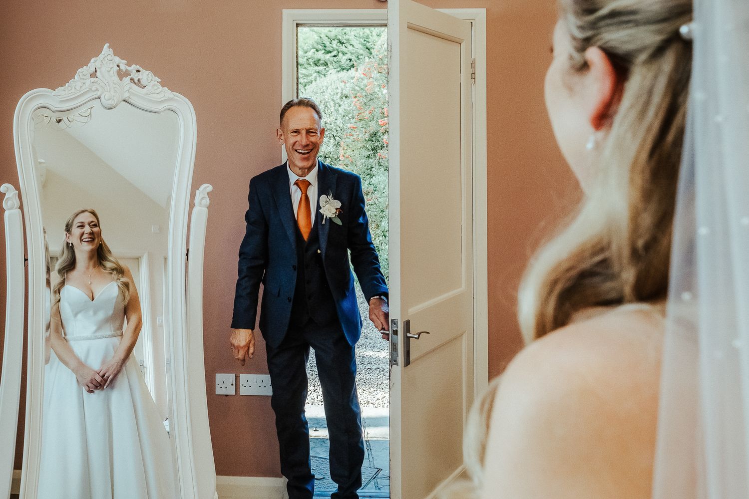 First look moment captured in elegant room with ornate mirror.
