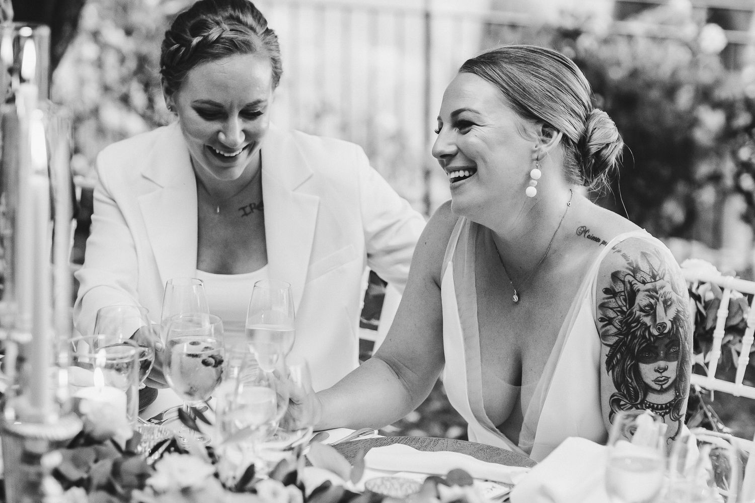 Black and white photo of wedding guests sharing laughter at outdoor reception.